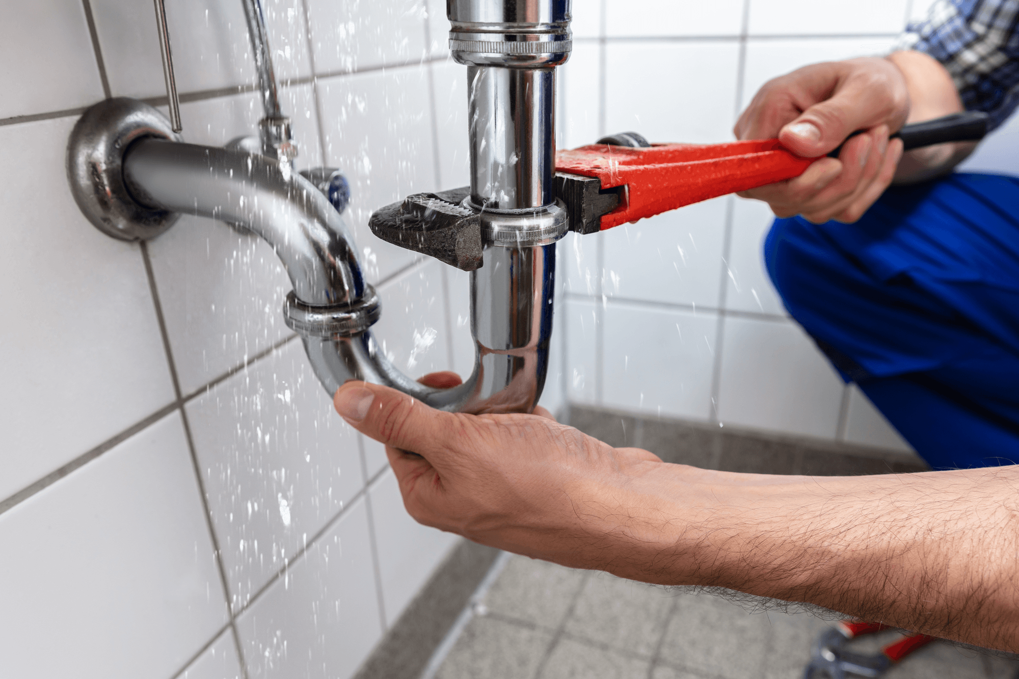 Plumber repairing pipes beneath a household sink